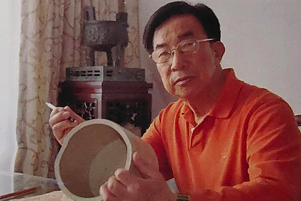 谭泉海大师在镌刻紫砂笔筒