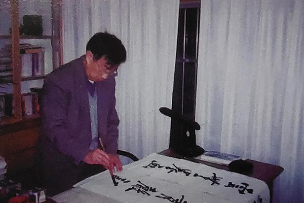 谭泉海在书房创作书法楹联